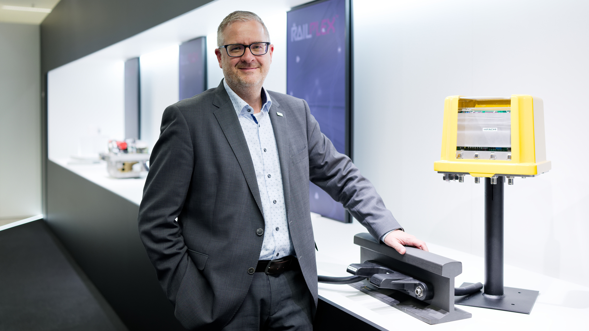 Markus Fritz presents a model of an axle counter in the Hitachi Rail showroom. It is highly significant for safety: The technology uses the attached sensors to report whether a section of track is clear. 