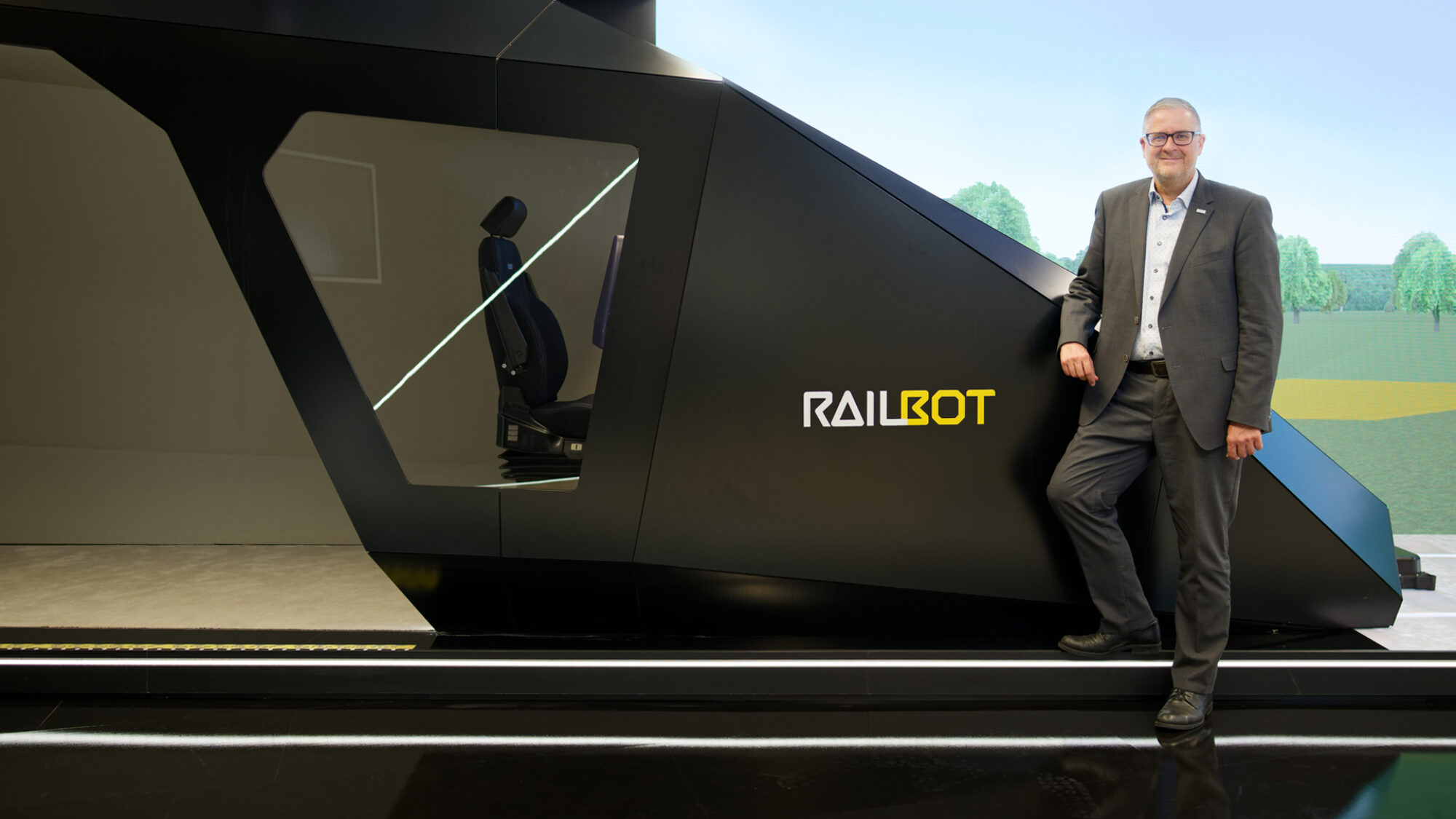 Vor dem „Railbot“ im Showroom von Hitachi Rail am Standort Ditzingen, nahe Stuttgart: In seiner Rolle als Vice President Markets Germany & Global Account Manager Deutsche Bahn, treibt Markus Fritz die Modernisierung des Schienenverkehrs in Deutschland voran.