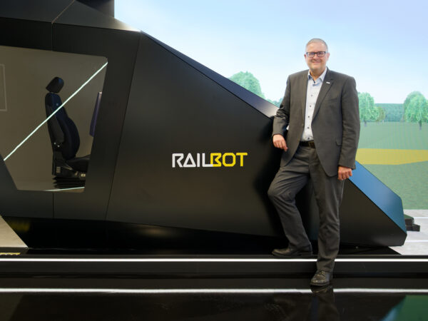 Vor dem „Railbot“ im Showroom von Hitachi Rail am Standort Ditzingen, nahe Stuttgart: In seiner Rolle als Vice President Markets Germany & Global Account Manager Deutsche Bahn, treibt Markus Fritz die Modernisierung des Schienenverkehrs in Deutschland voran.