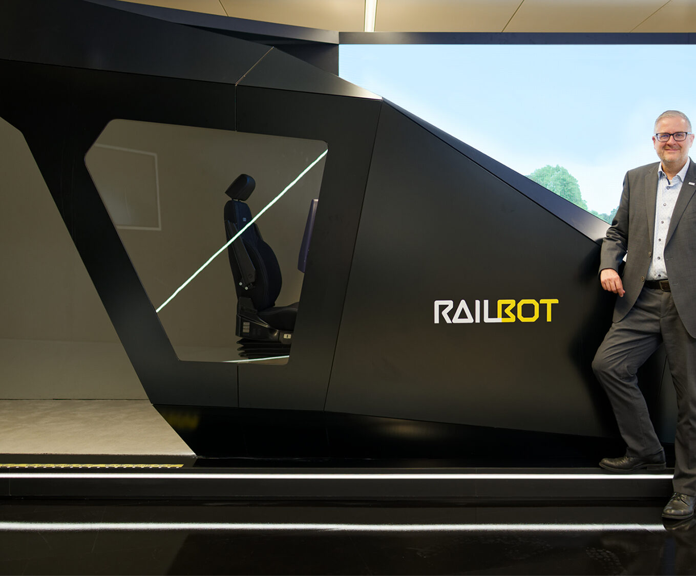 Vor dem „Railbot“ im Showroom von Hitachi Rail am Standort Ditzingen, nahe Stuttgart: In seiner Rolle als Vice President Markets Germany & Global Account Manager Deutsche Bahn, treibt Markus Fritz die Modernisierung des Schienenverkehrs in Deutschland voran.
